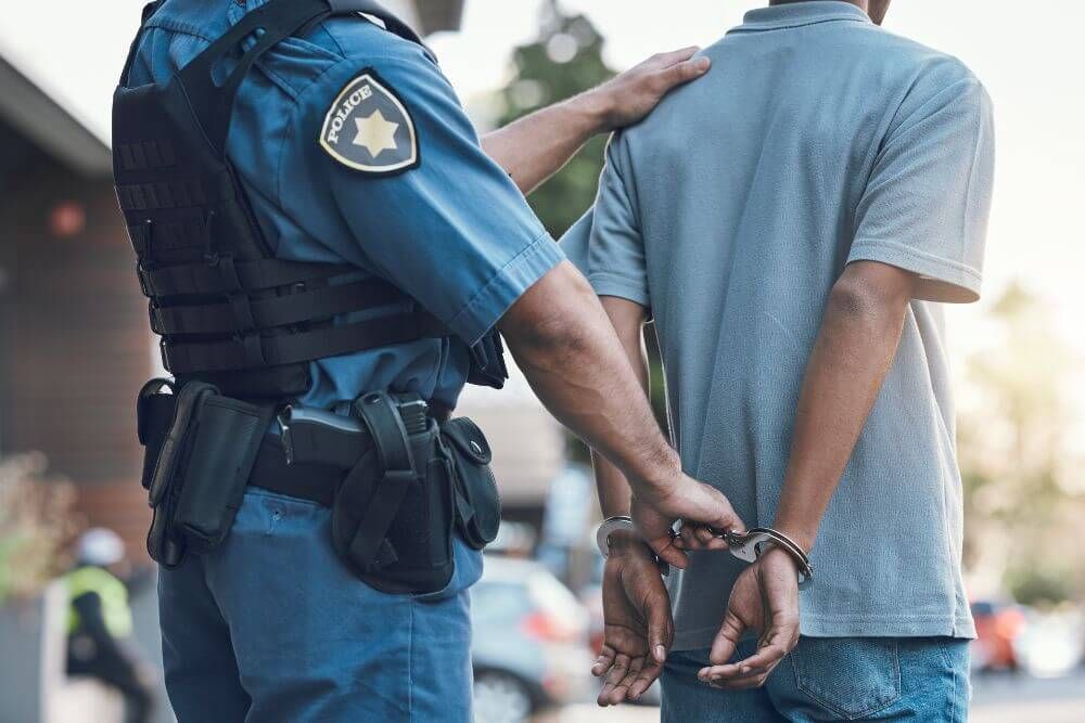 image of police officer guiding a man in handcuffs