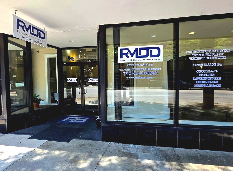 Front of law firm office RMDD, glass windows, signage with phone number and website, sunny street view.