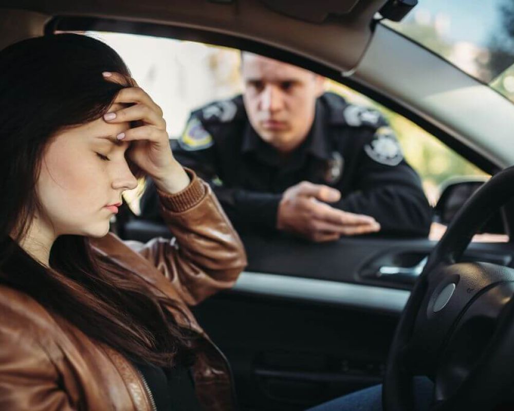 image of a driver frustrated looking down as police officer explains the traffic infraction in the window