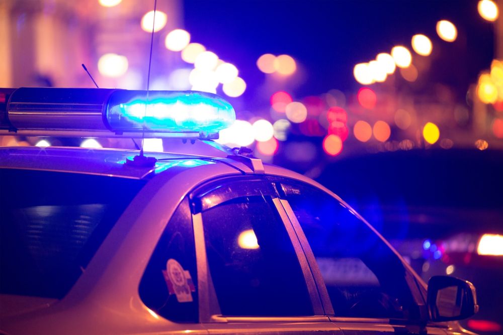 Police car with flashing blue lights at night, street in bokeh background.