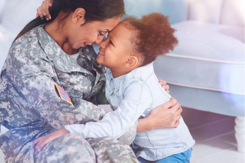 a woman in a military uniform hugging a small child