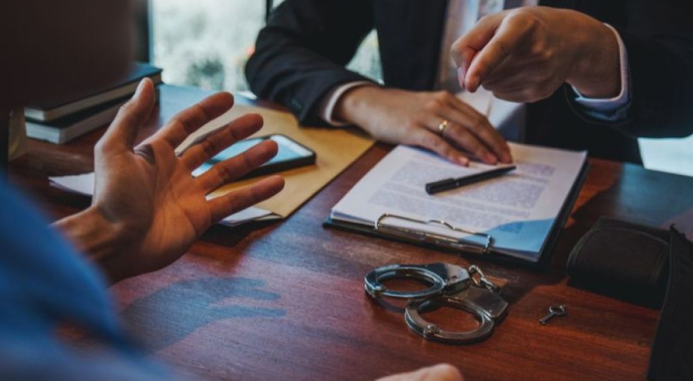 Criminal defense lawyer discussing clients case with handcuffs on the office desk