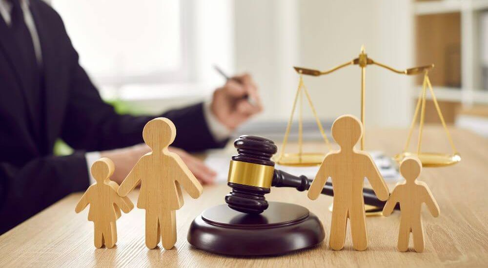 Family law concept with wooden figures, gavel, and scales of justice on a lawyer's desk.