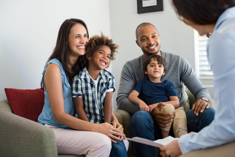 Smiling family having a consultation with a professional in a cozy living room setting.