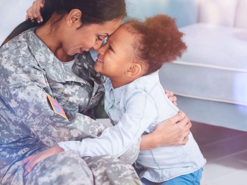 a woman in a military uniform hugging a small child