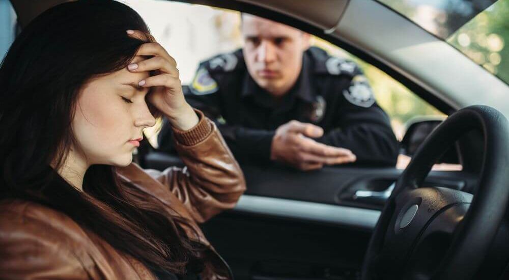 image of a driver frustrated looking down as police officer explains the traffic infraction in the window