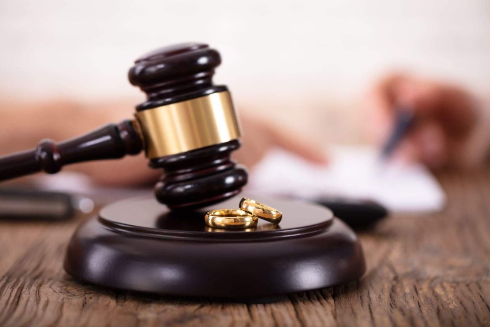 a judge's gavel with two gold wedding rings on it