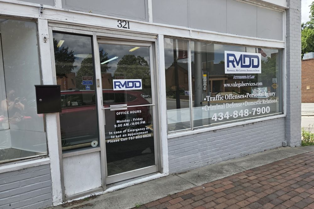 Law office storefront with RMDD logo, offering legal services like personal injury and criminal defense. Office hours displayed.