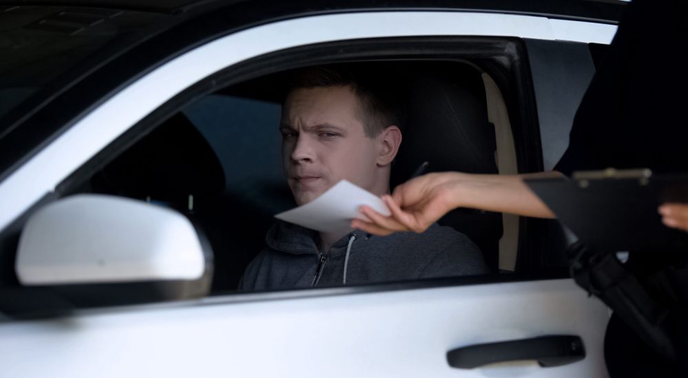 image of police woman giving fine receipt to driver on road, traffic offence, inspection