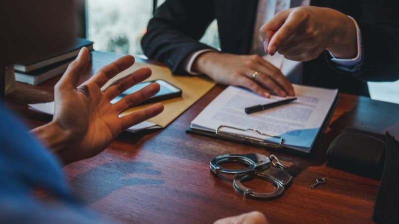 Criminal defense lawyer discussing clients case with handcuffs on the office desk