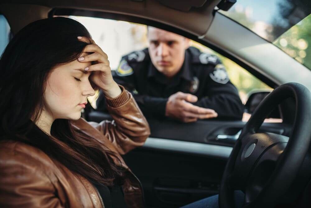 image of a driver frustrated looking down as police officer explains the traffic infraction in the window