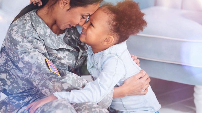 a woman in a military uniform hugging a small child