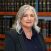 Tammy McClenney in a suit poses confidently in a library with legal books. Business, expertise, and elegance.