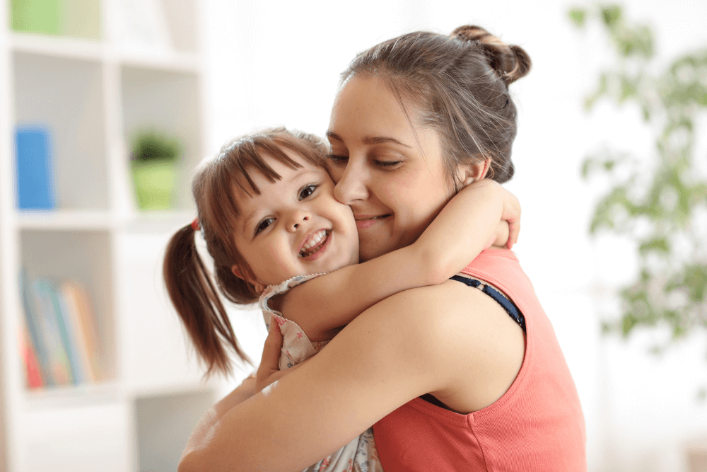 woman hugging small child with both of them smiling