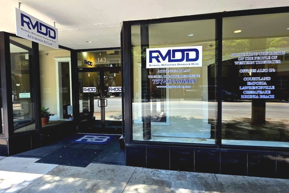 Front of law firm office RMDD, glass windows, signage with phone number and website, sunny street view.