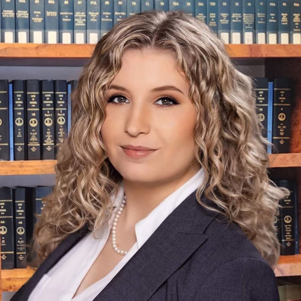 Professional woman in suit with curly hair in front of law bookshelves.