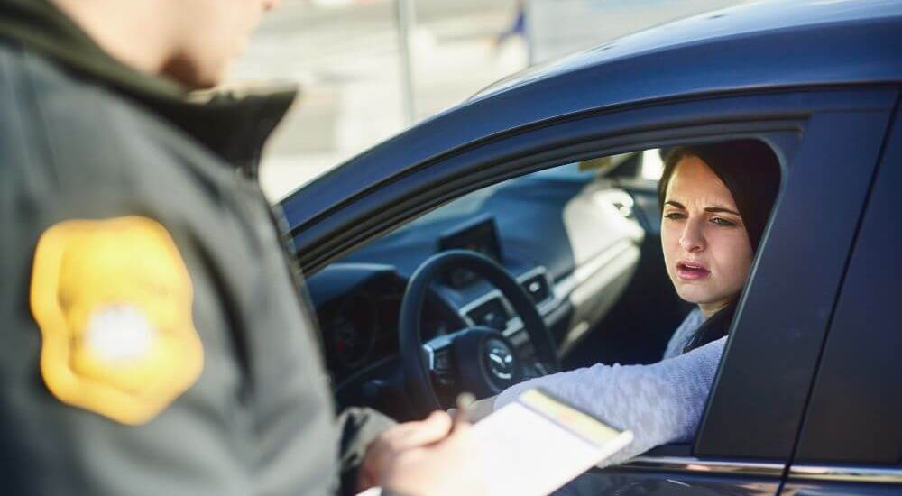image of a police officer writing a ticket for a person outside their vehicle window on the side of the road