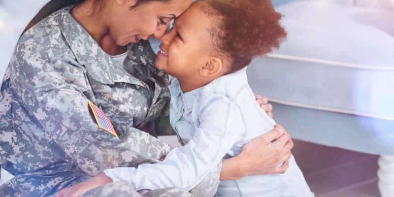a woman in a military uniform hugging a small child
