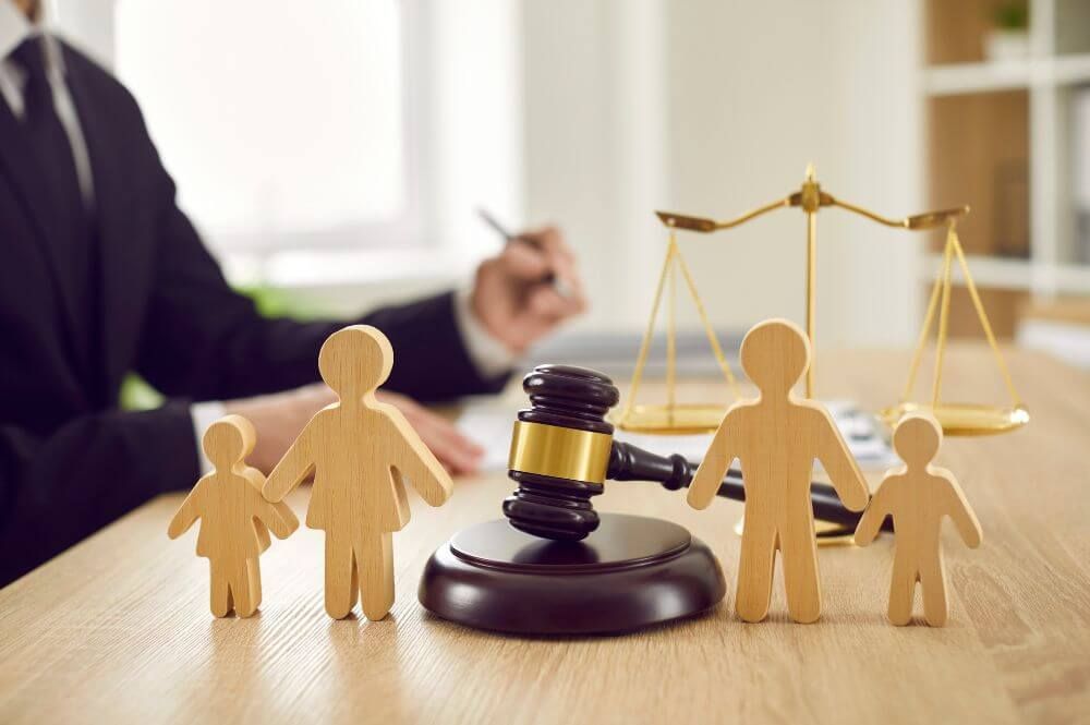 Family law concept with wooden figures, gavel, and scales of justice on a lawyer's desk.