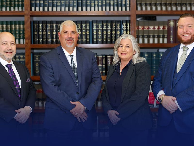 Randall, McClenney, Daniels & Dunn in formal attire standing in a library with law bookshelves.