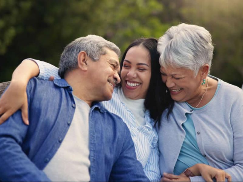 Family enjoying happy moments together outdoors on a wooden bench.