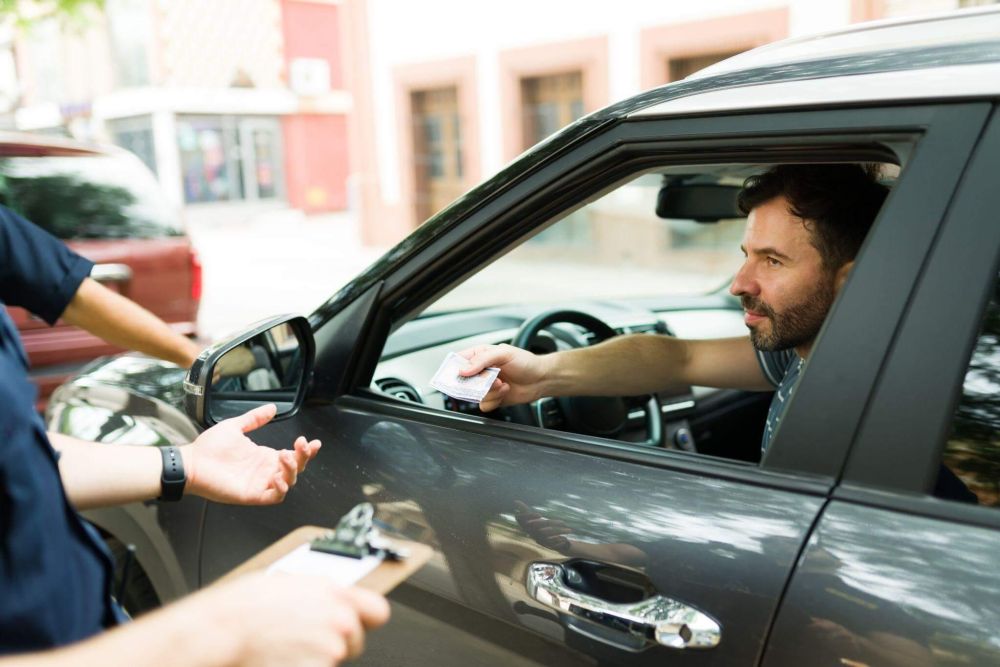 a man inside of a car is handing his license to the police