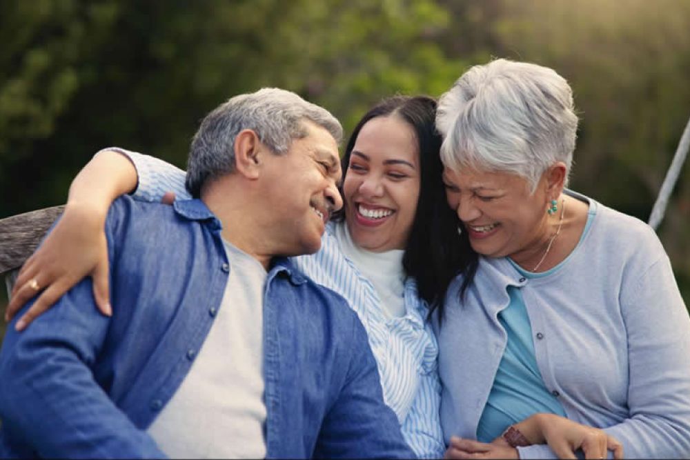 Family enjoying happy moments together outdoors on a wooden bench.