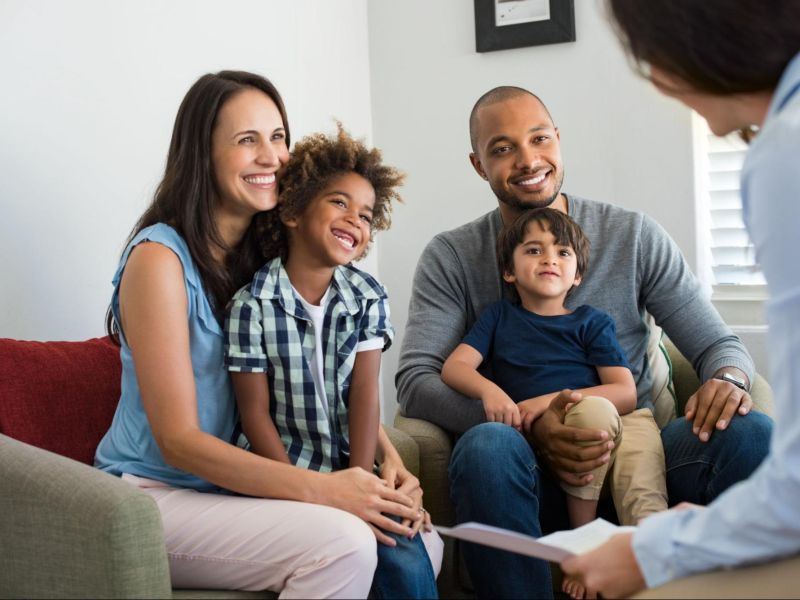 Smiling family having a consultation with a professional in a cozy living room setting.