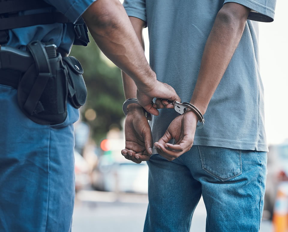 Police officer handcuffing a person during an arrest on the street.