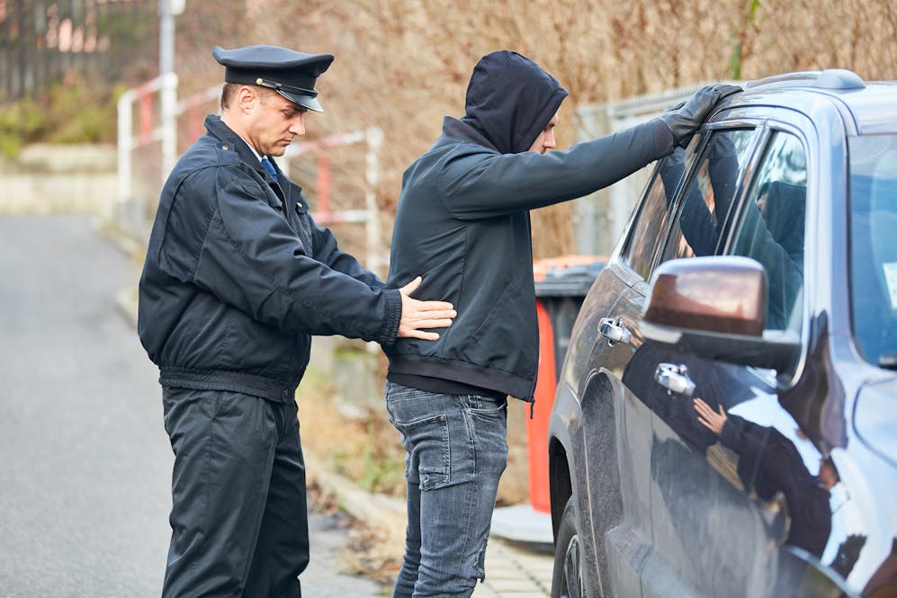 image of police officer searching a man with his hands on the top of a vehicle