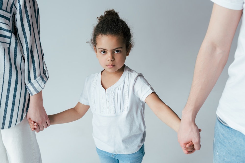 Child holding hands with two adults, symbolizing family support and connection, wearing casual clothes.