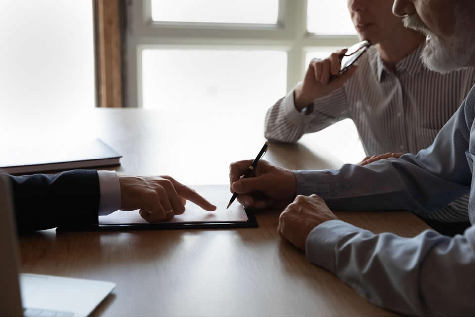 Business team discussing contract details with a tablet on a wooden table, highlighting collaboration in a modern office setting.