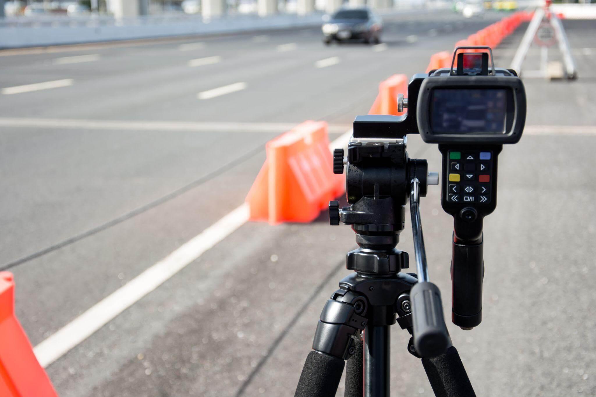 a speed meter on a tripod on the side of a road