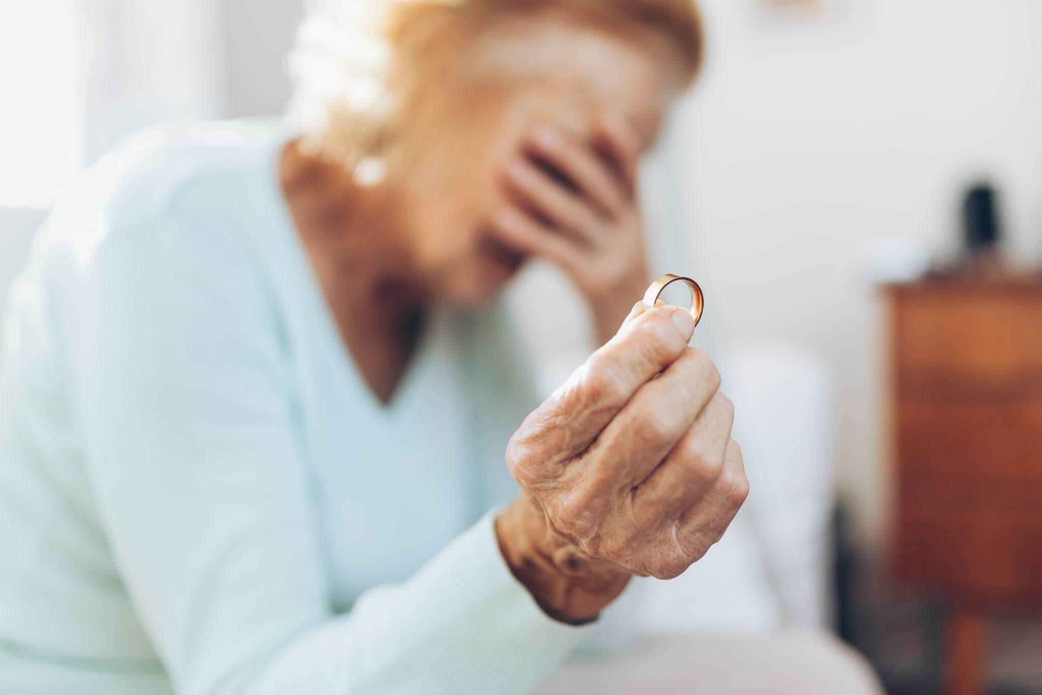 a woman holding a wedding ring in her hand, she seems distressed
