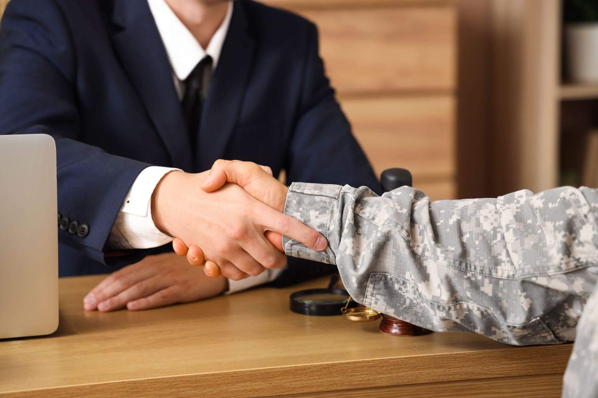 two people shaking hands in front of a laptop