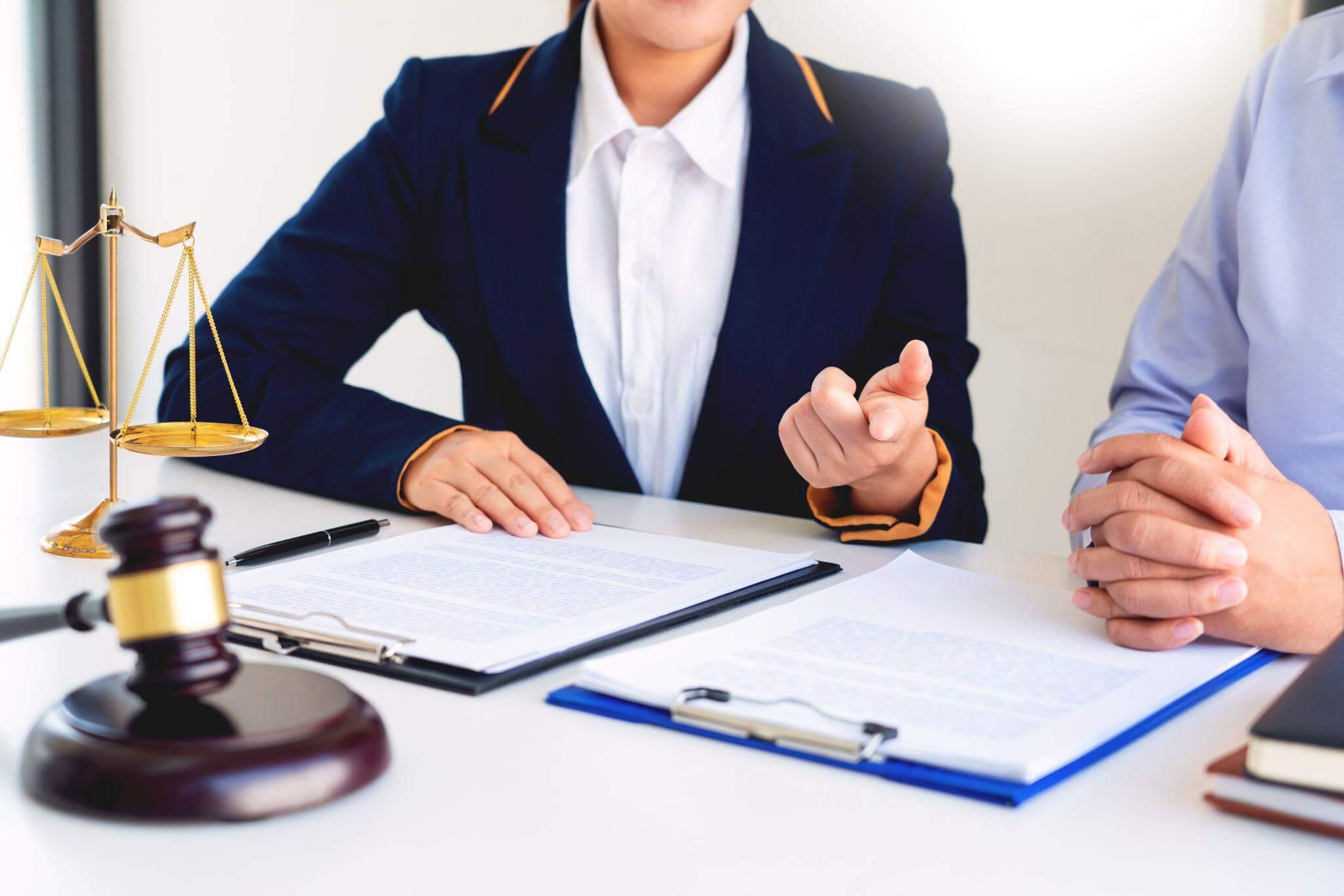 two people sitting at a table in front of a scale of justice